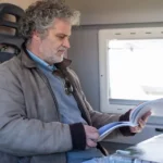 man met boek op trein